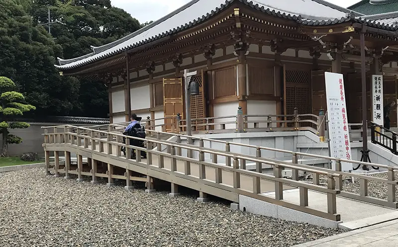 A person using a power wheelchair going up an acccessible ramp at a Japanese temple