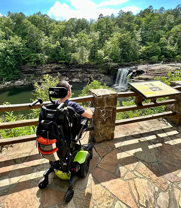 Cory using power seat elevate to see a waterfall over a railing